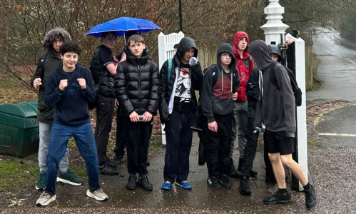 All the students standing  in a group in the rain near the end of the walk